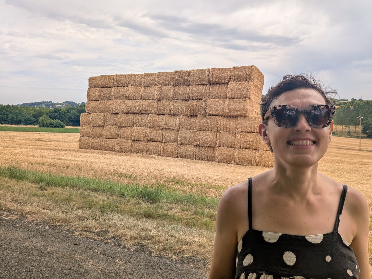 Inna Shchepanska smiling in a field beside stacked hay bales